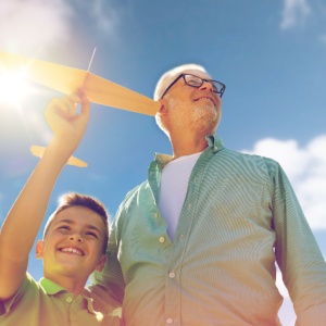 A grandfather and grandson playing with a toy plane outdoors.