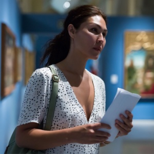 A woman in a museum looks at an art exhibition.